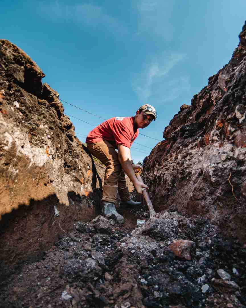 A detailed shot of a trench being dug for utility installation, showcasing precision and safety measures. - Reliable